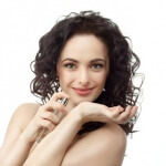 closeup portrait of attractive caucasian smiling woman brunette isolated on white studio shot lips face hair head and shoulders looking at camera applying perfume